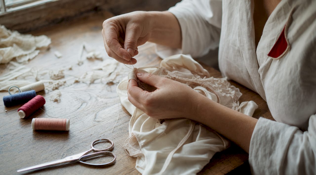 Des mains expertes confectionnent à la main de la lingerie fine en soie naturelle.
