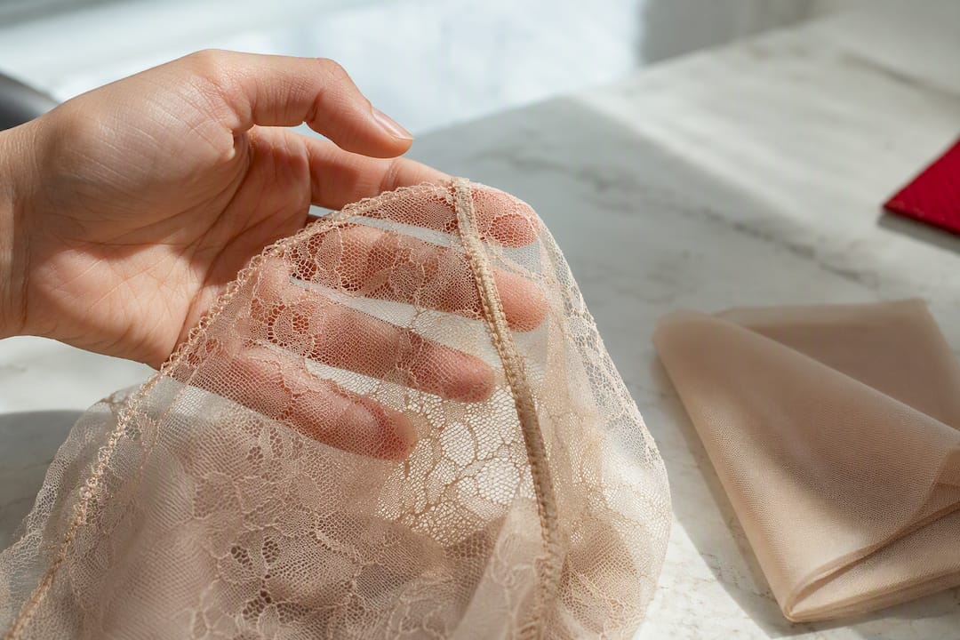 Main contrôlant une couture en dentelle