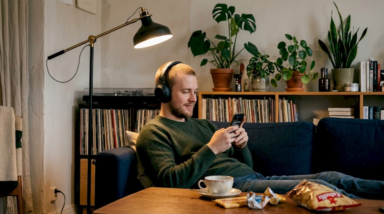 Ung kille slappnar av i soffan hemma och njuter av sin favoritmusik.