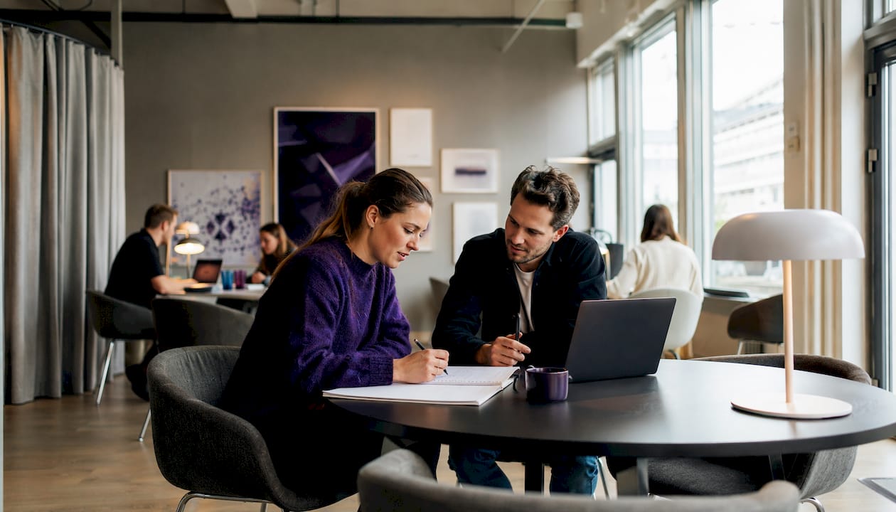 Två företagare jobbar tillsammans och utbyter idéer i en inspirerande coworkingmiljö.
