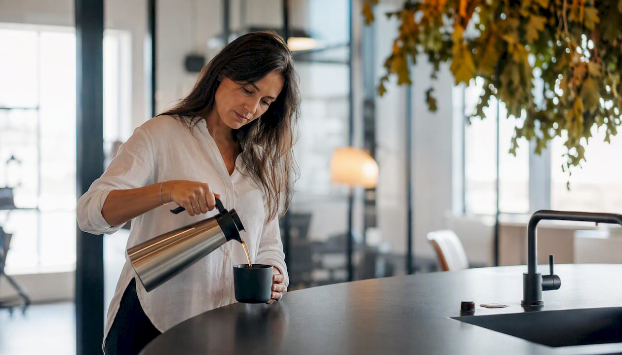 Någon häller upp kaffe i en mugg i det gemensamma köket på kontoret.