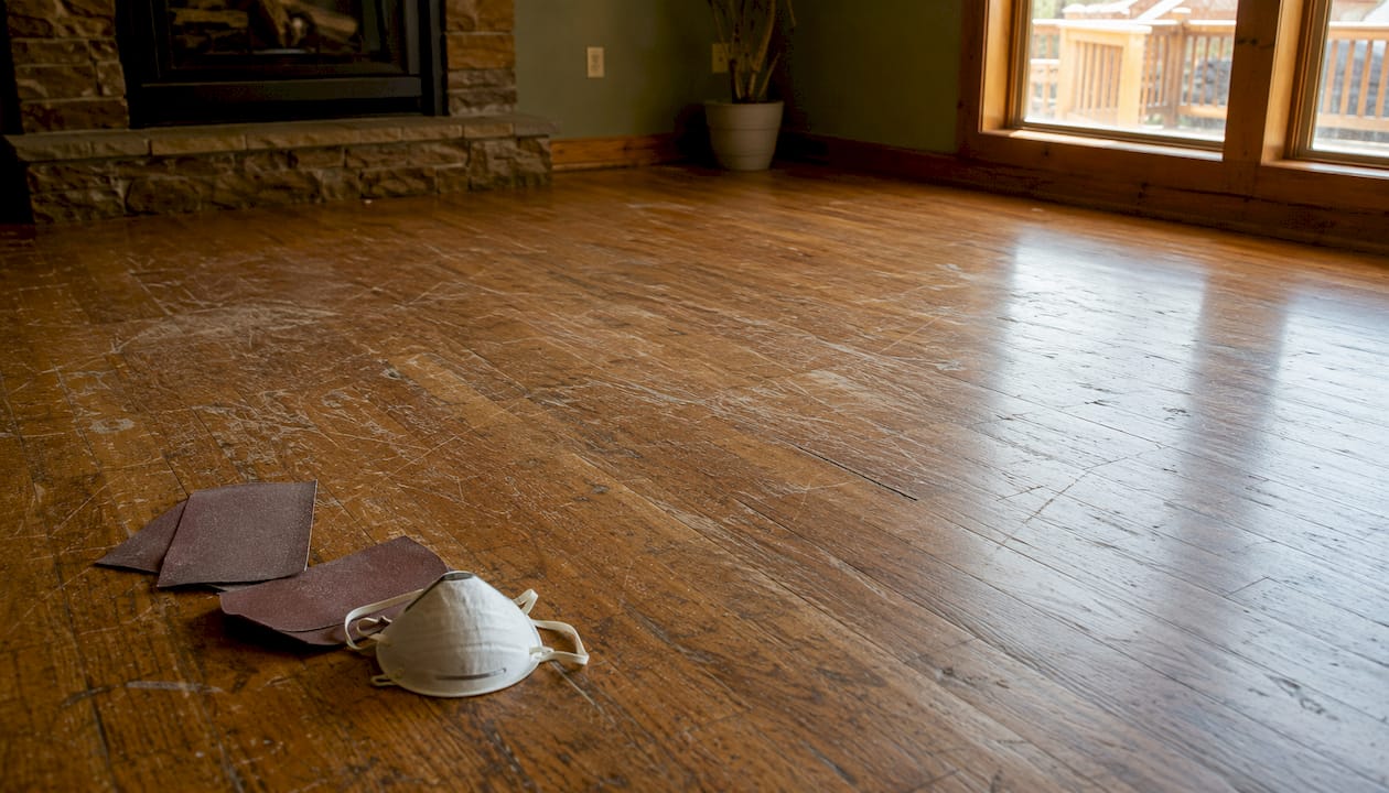 Worn scratched hardwood floor with sanding tools
