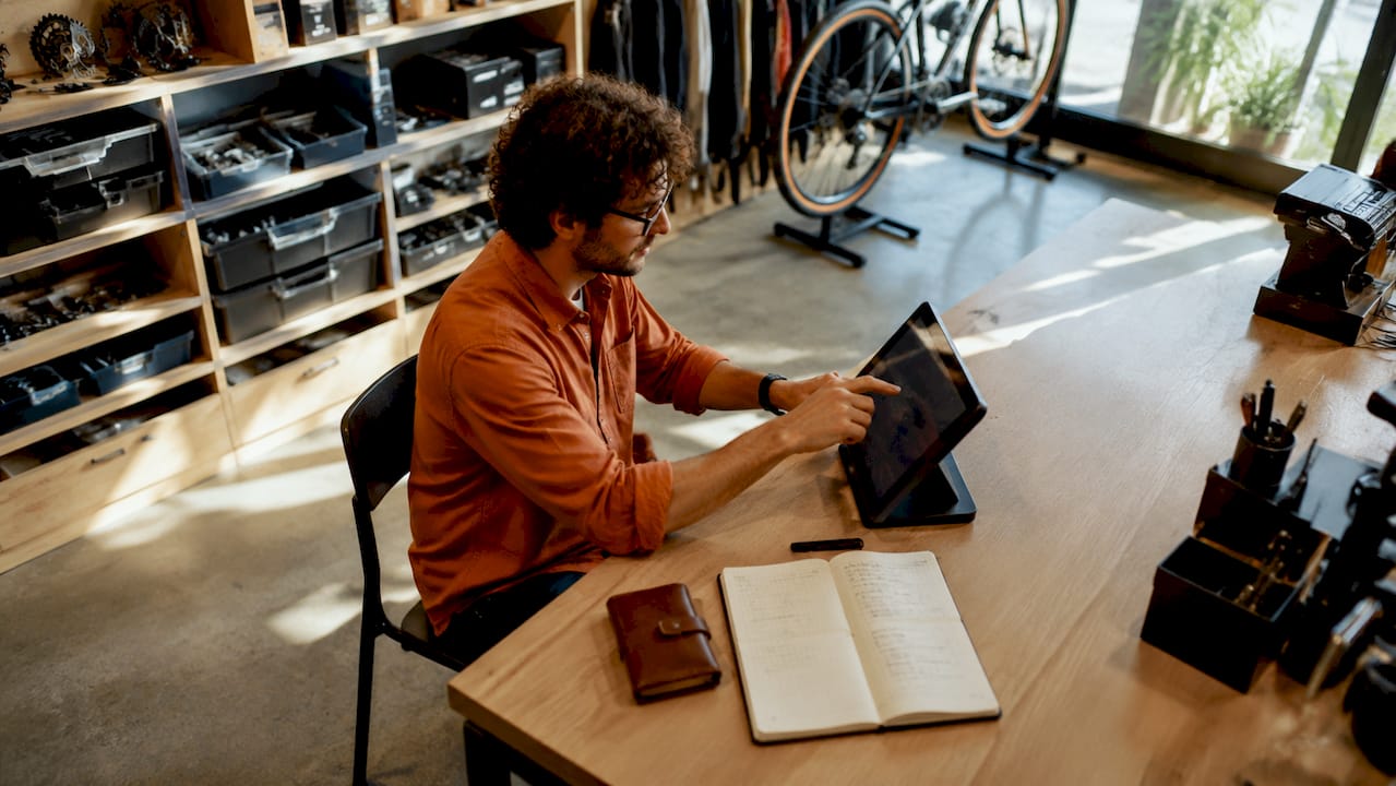 Des mains manipulent un écran tactile de caisse sur un vélo.