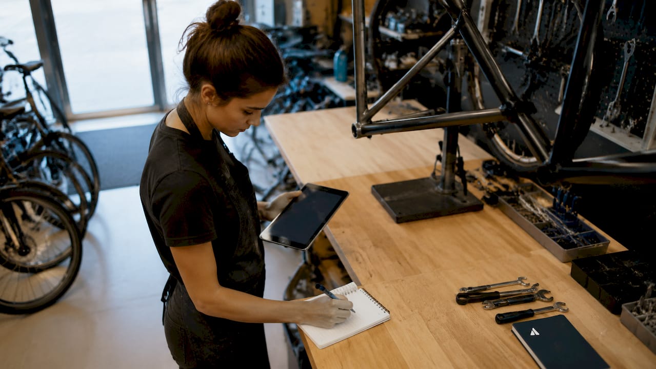 Un mécanicien vélo consulte les informations de réparation de ses clients directement sur sa tablette.
