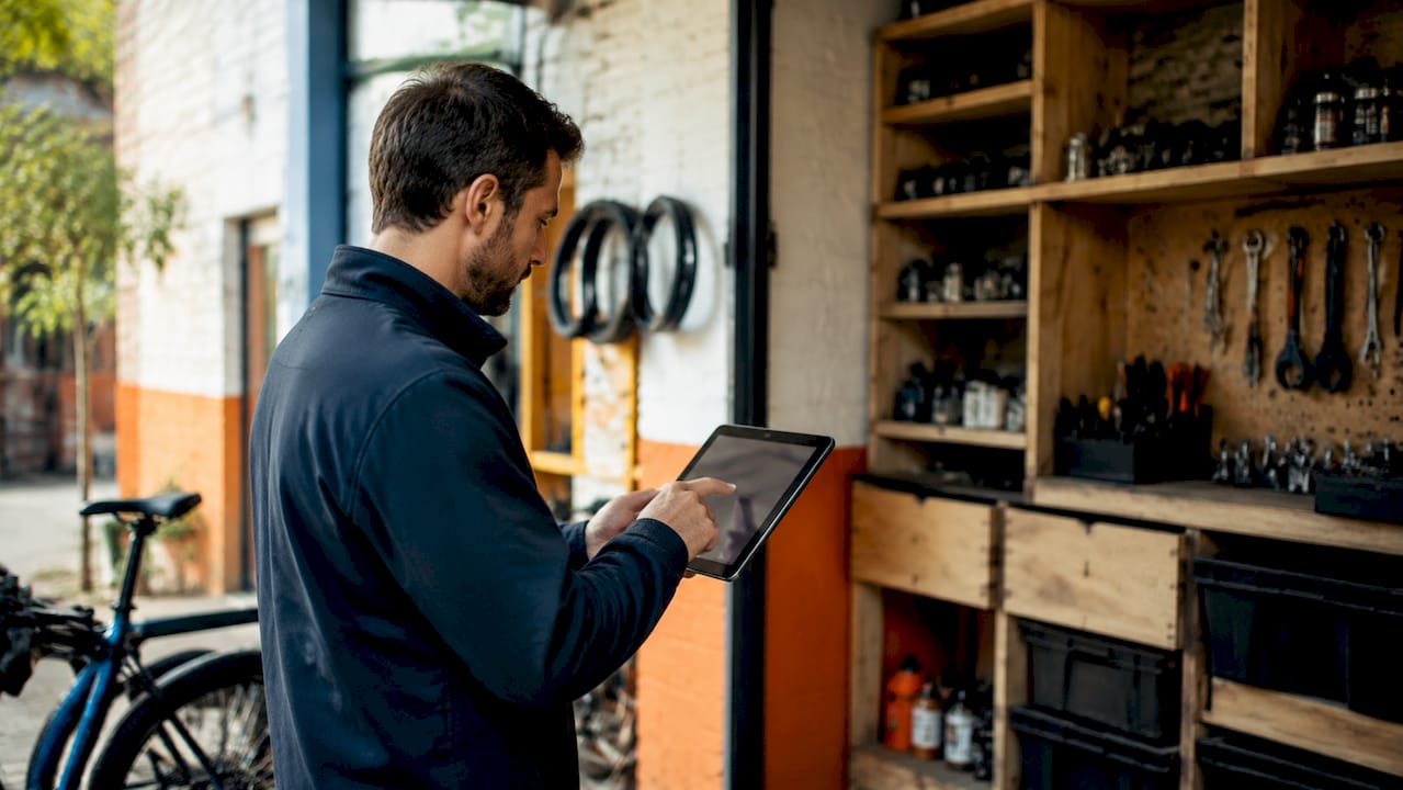 Un artisan manipule un cadre sur une tablette, en plein atelier.