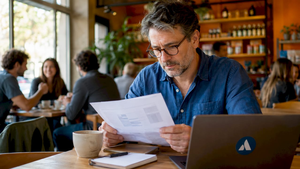 Un commerçant consulte attentivement une notice concernant la conformité de sa caisse enregistreuse à la norme NF525.