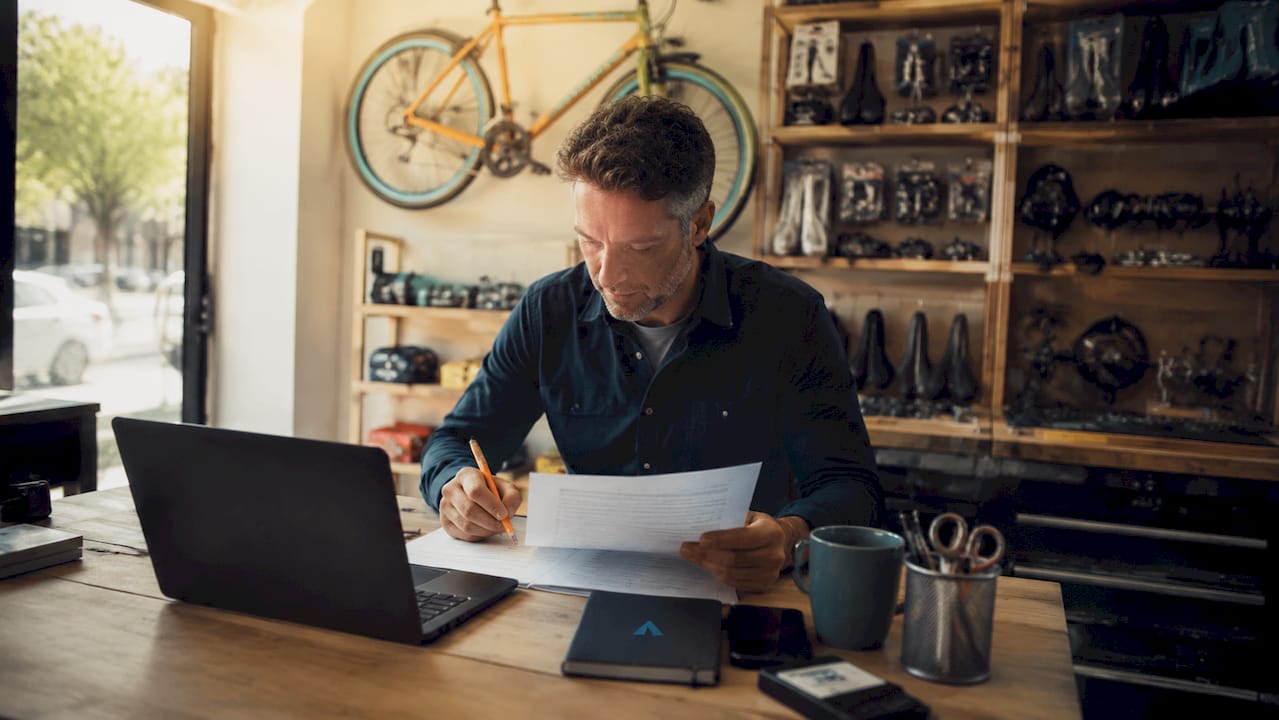 Le gérant d’un magasin de vélos passe en revue ses factures derrière son bureau.