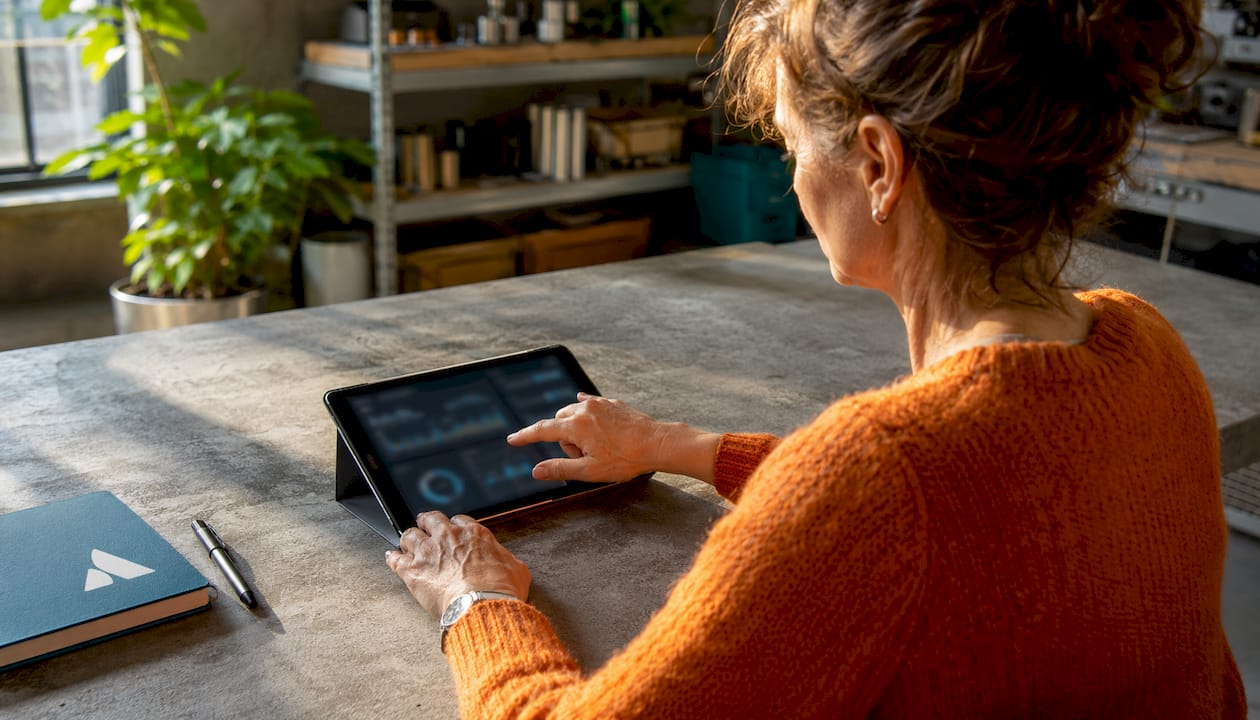 Une main utilise une tablette tactile dans un bureau respectueux de l’environnement.