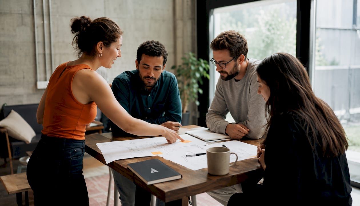 Une équipe réunit ses idées et travaille ensemble autour d’une table de travail.