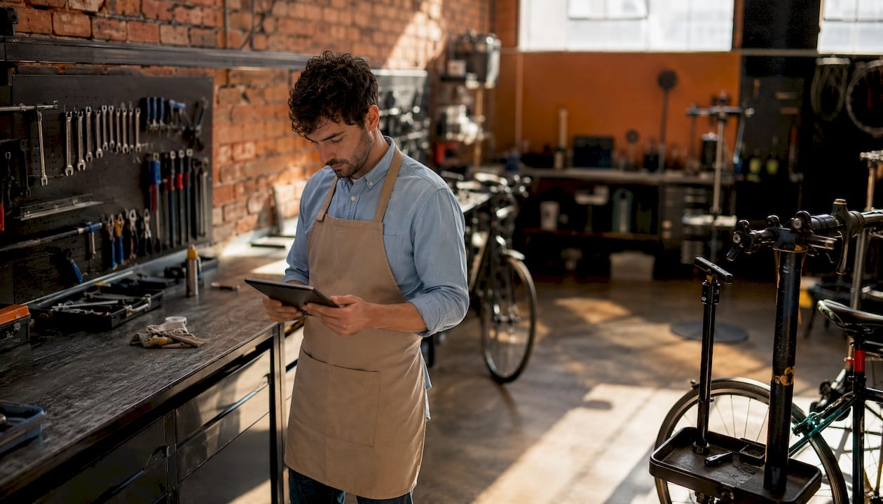 Un mécanicien vélo consulte une tablette au cœur de son atelier.