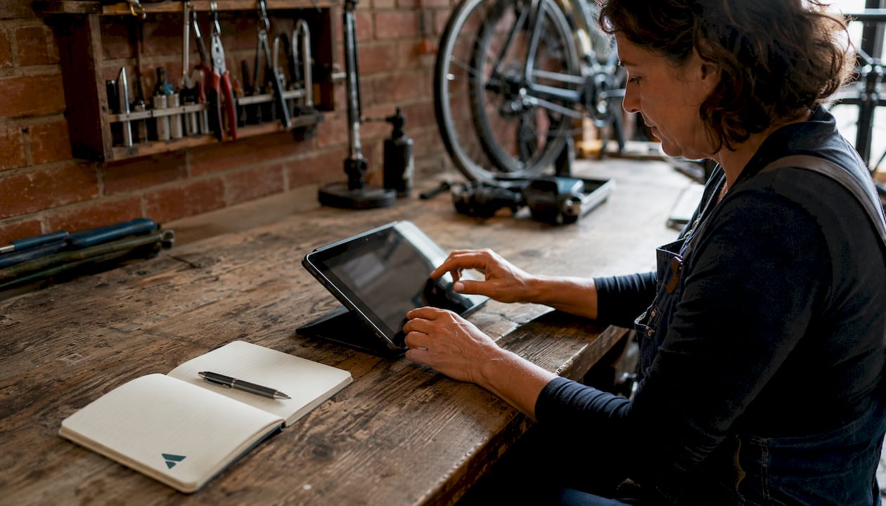 Une femme consulte une tablette numérique dans un atelier de réparation de vélos.