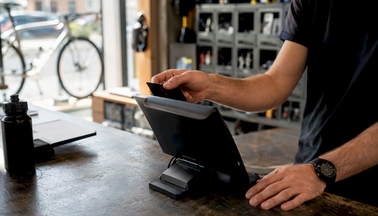 Un vendeur de vélos en train d'encaisser un client à la caisse du magasin.