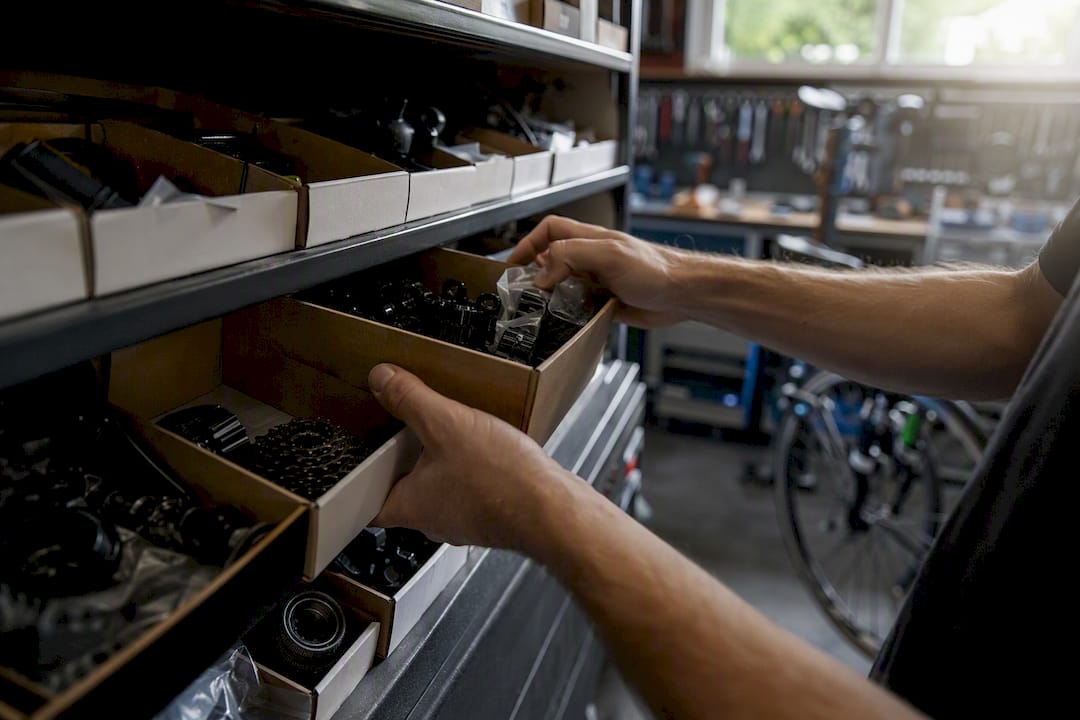 Des mains rangent et mettent à jour le stock de pièces de vélo sur les étagères.