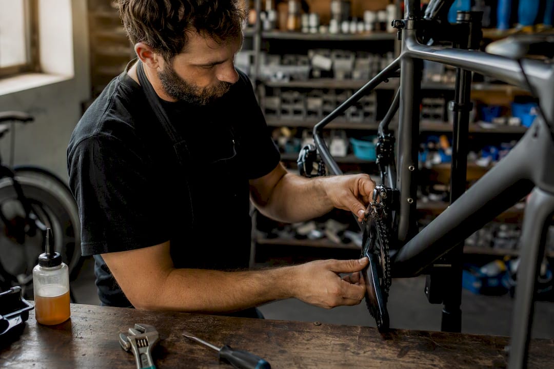 Des mains s’affairent à monter un composant de vélo dans l’atelier.
