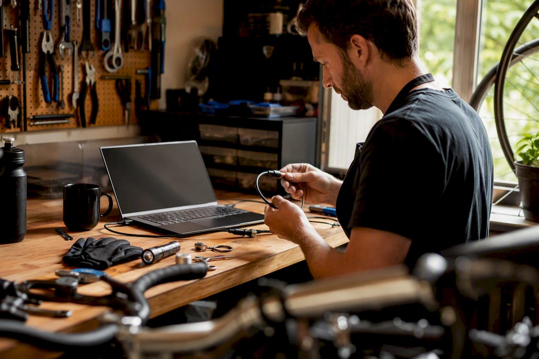 Un technicien installe un câble antivol sur un vélo dans l’atelier.