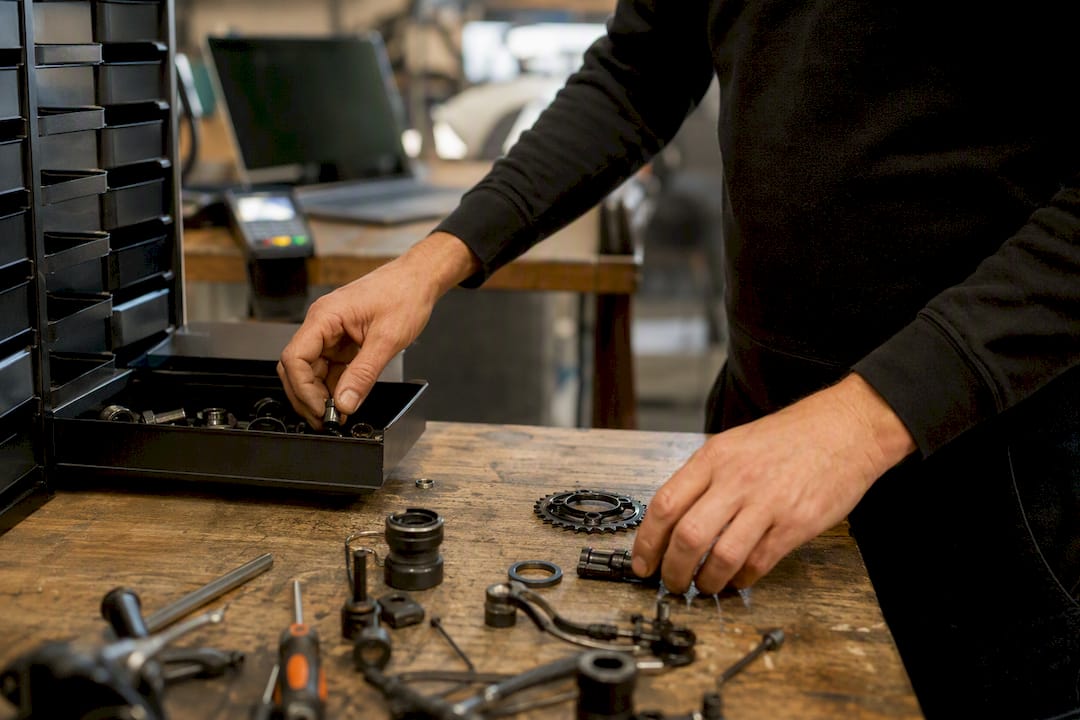 Des mains manipulant des pièces de vélo dans un atelier