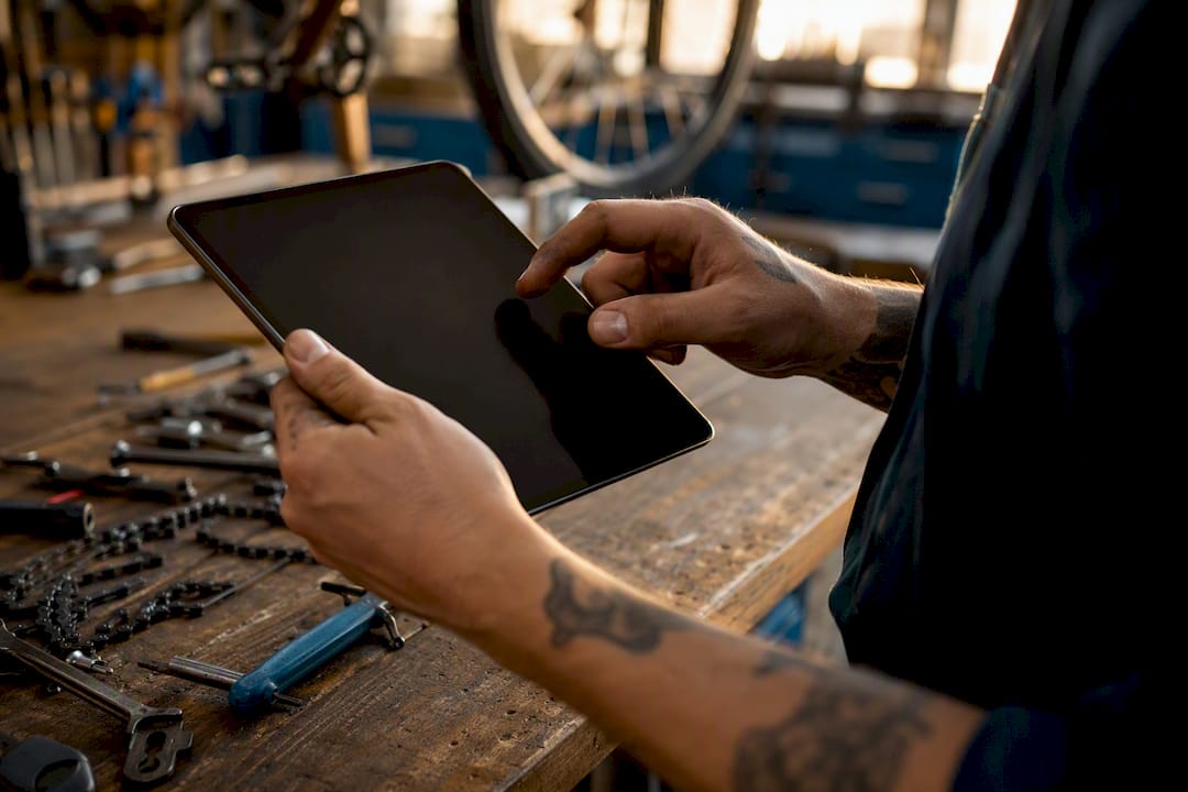 Mains naviguant sur une tablette de facture dans un atelier de vélos