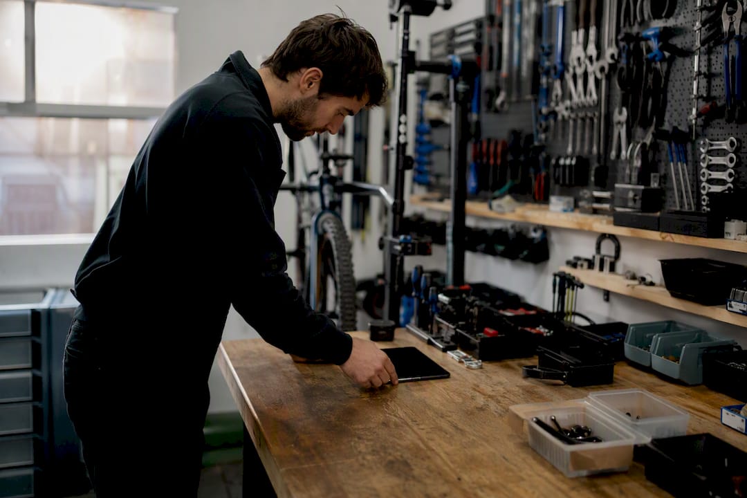 Deux paires de mains s'échangent un appareil dans un atelier de vélos