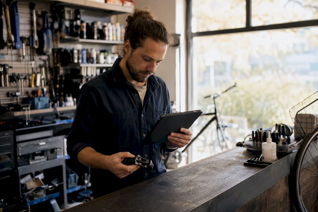Mains d'un technicien avec une tablette dans un atelier de vélos