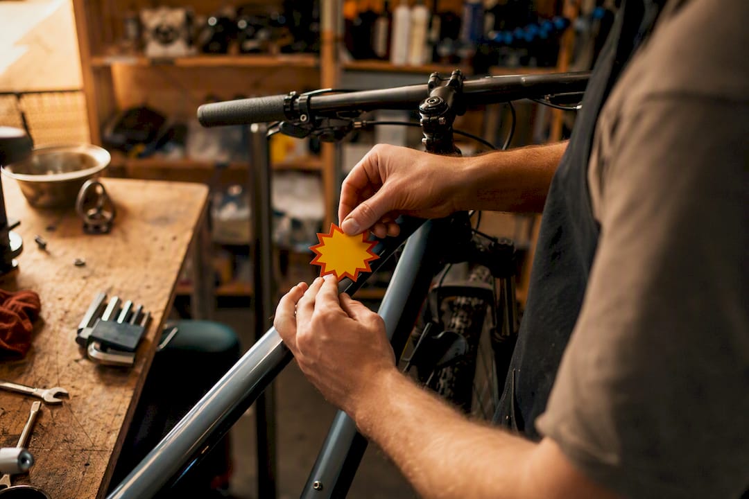 Mains apposant un autocollant promotionnel sur un vélo