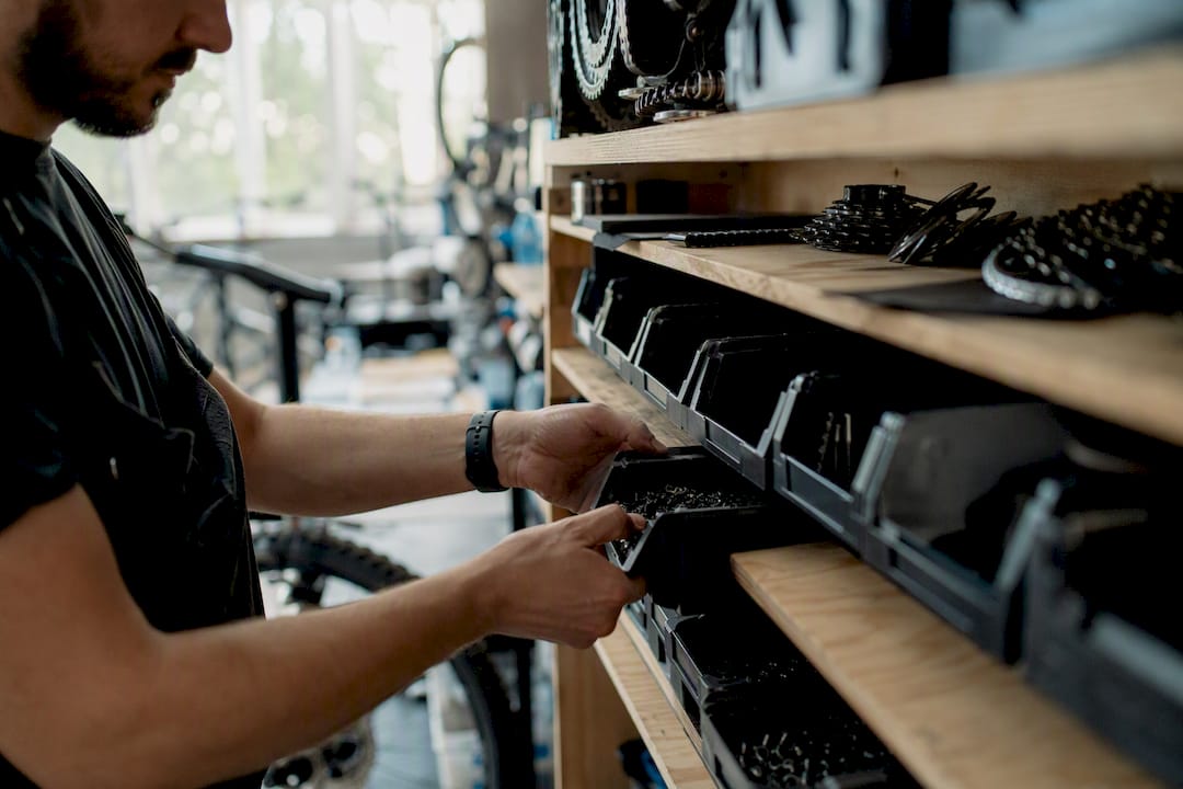 Mains rangeant des pièces de vélo sur une étagère d'atelier