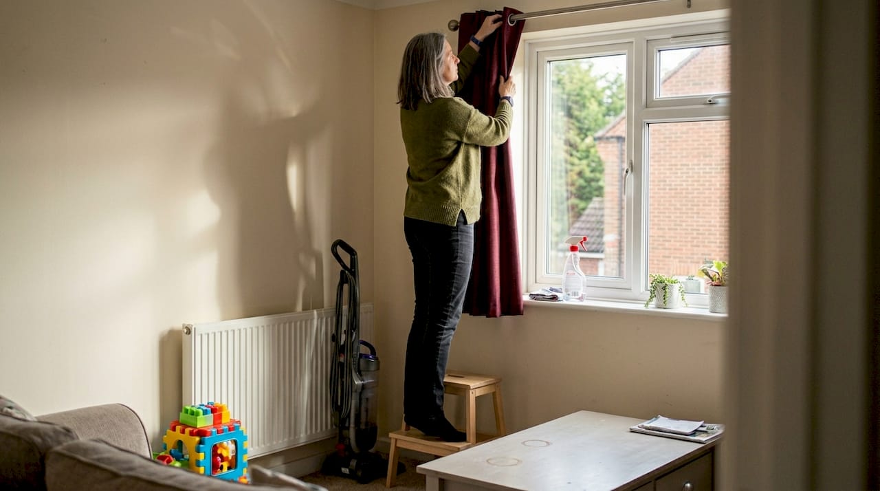 Woman removing curtain for cleaning in UK home