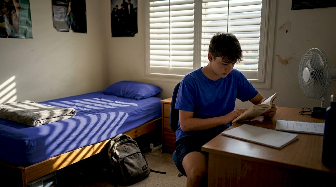 Summer bedroom with closed shutters and reading boy