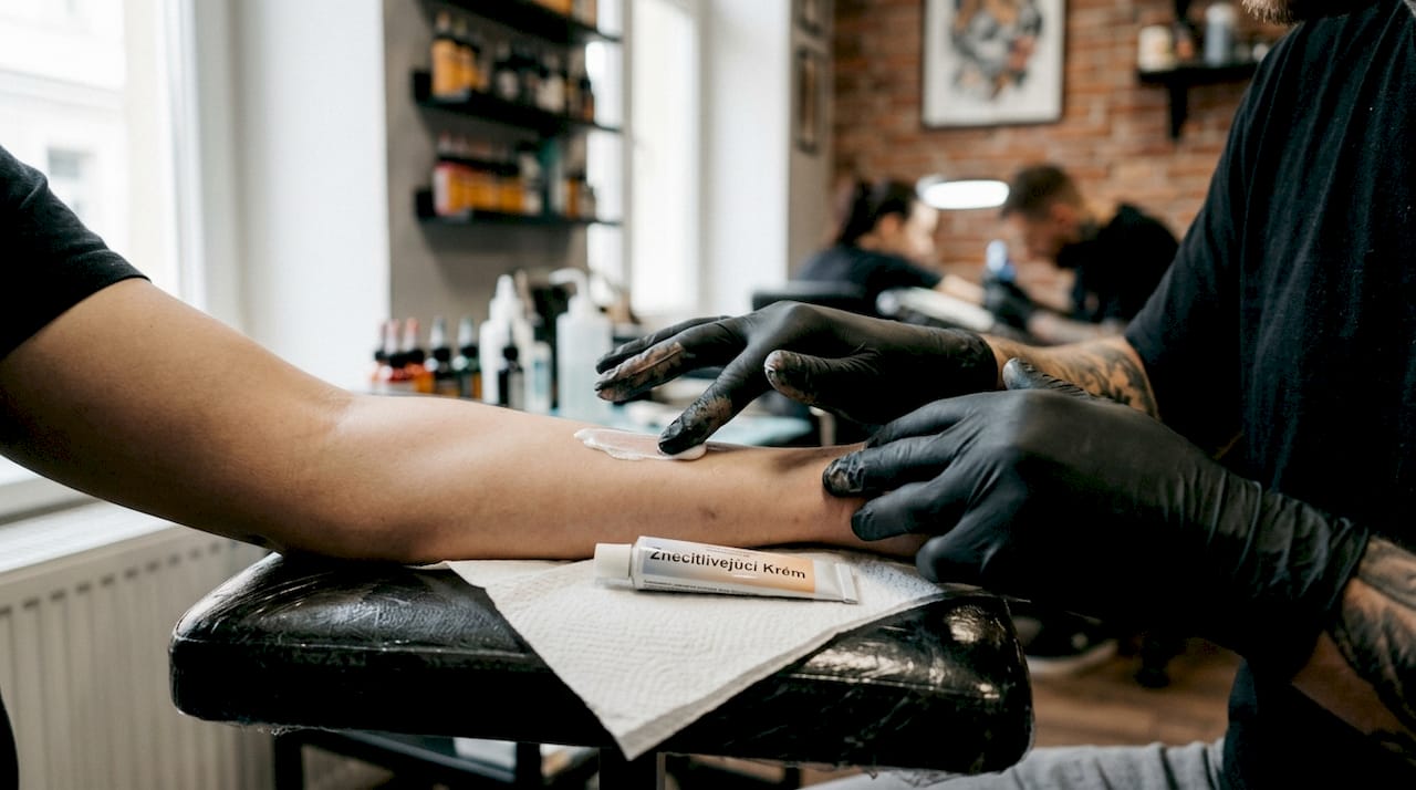 Nanášanie anestetického krému na pokožku pred tetovaním v štúdiu