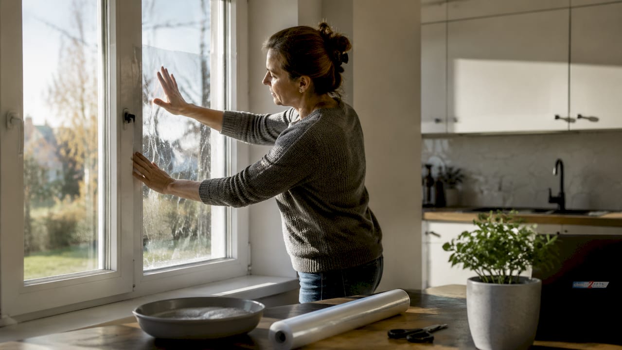 Close-up hands installing window insulation film