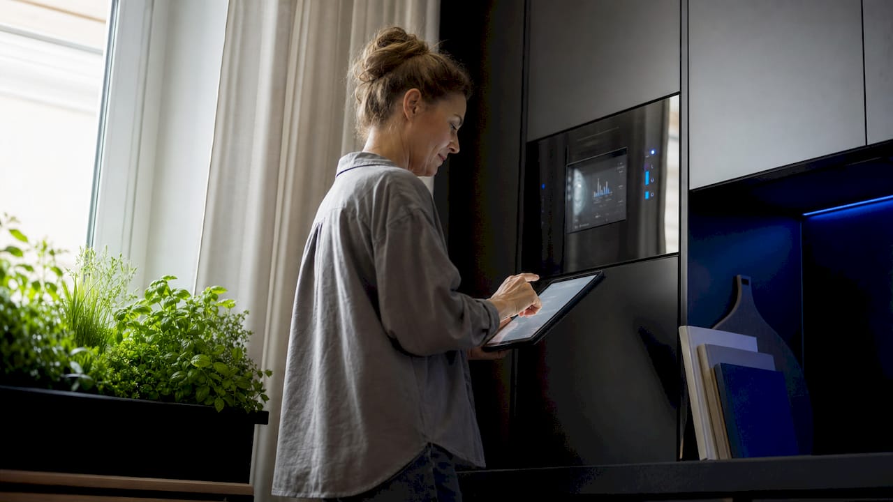 European woman checking smart energy meter with tablet