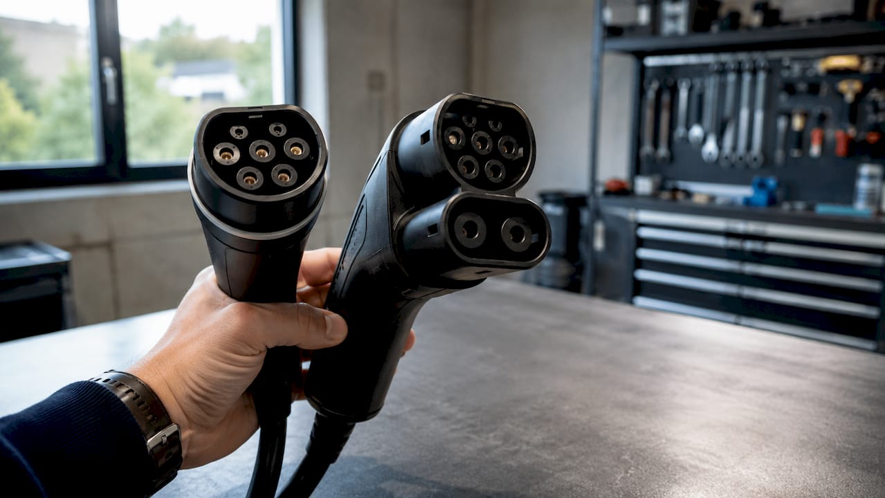 Main tenant des prises de recharge pour voitures électriques, compatibles avec le courant alternatif et continu