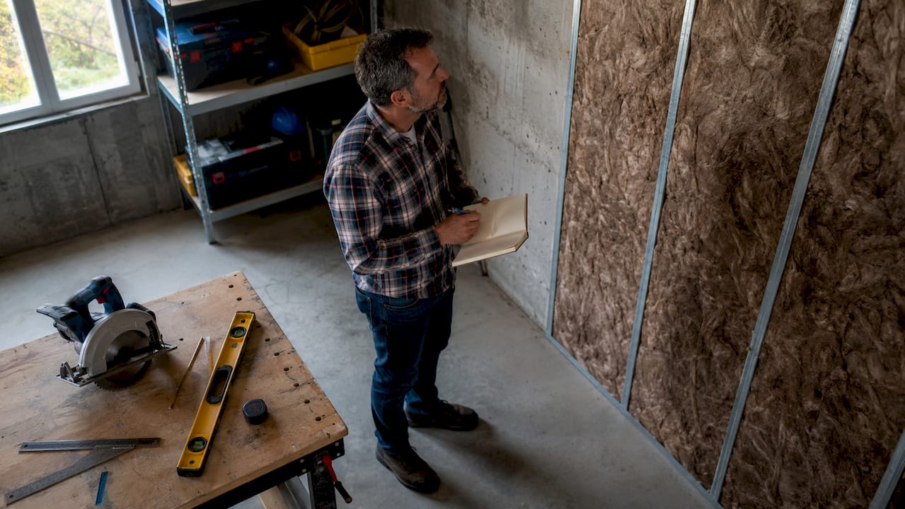 Un expert en efficacité énergétique procède à un contrôle de l’isolation des combles dans une maison.
