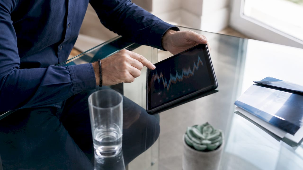 Des mains consultent et manipulent un graphique des tarifs de l’électricité sur une tablette.