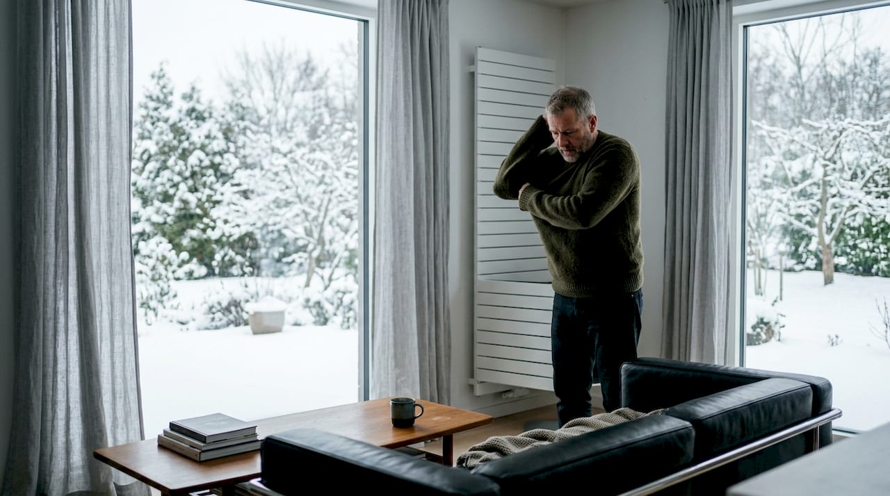 Dans une maison équipée d’un thermostat, un homme règle la température du chauffage pour plus de confort.