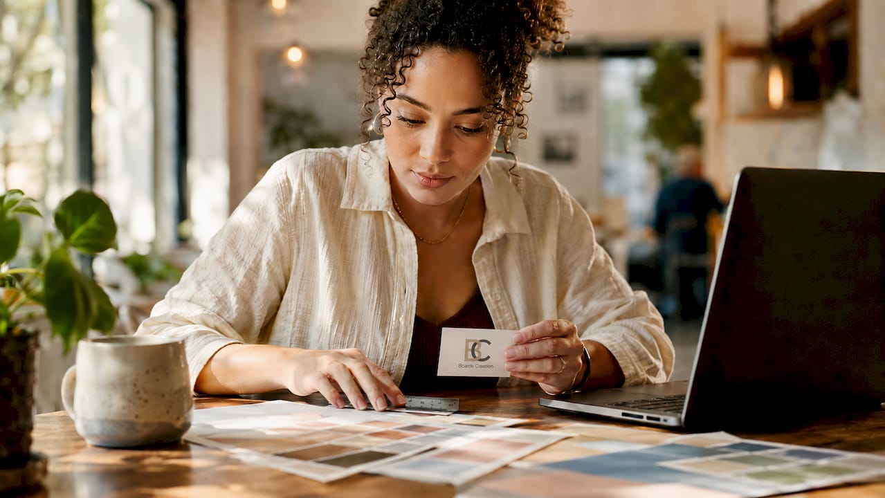 Woman reviewing printed business card at desk