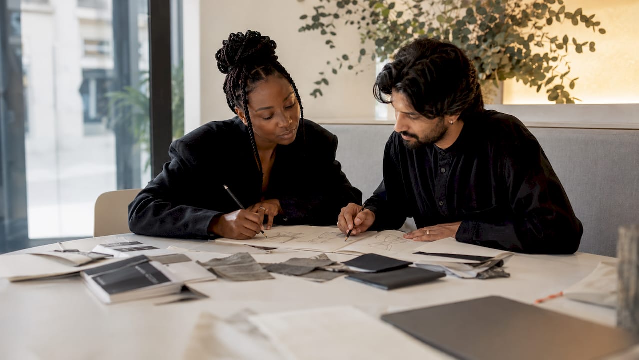 Designerinnen und Designer tauschen sich gemeinsam über Entwürfe und Stoffmuster aus.