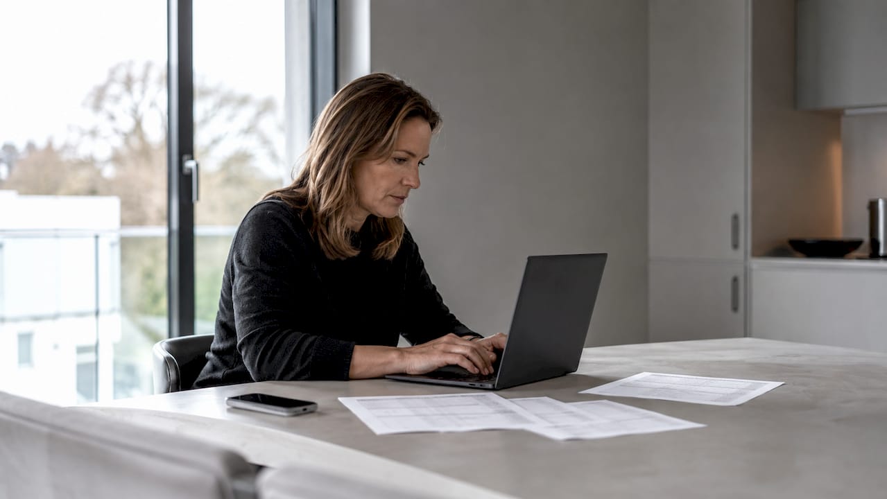 Eine Frau sitzt zu Hause am Laptop und vergleicht online Preise.