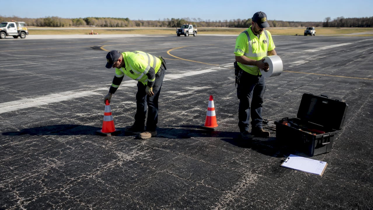 Workers preparing tools for airport surface treatment