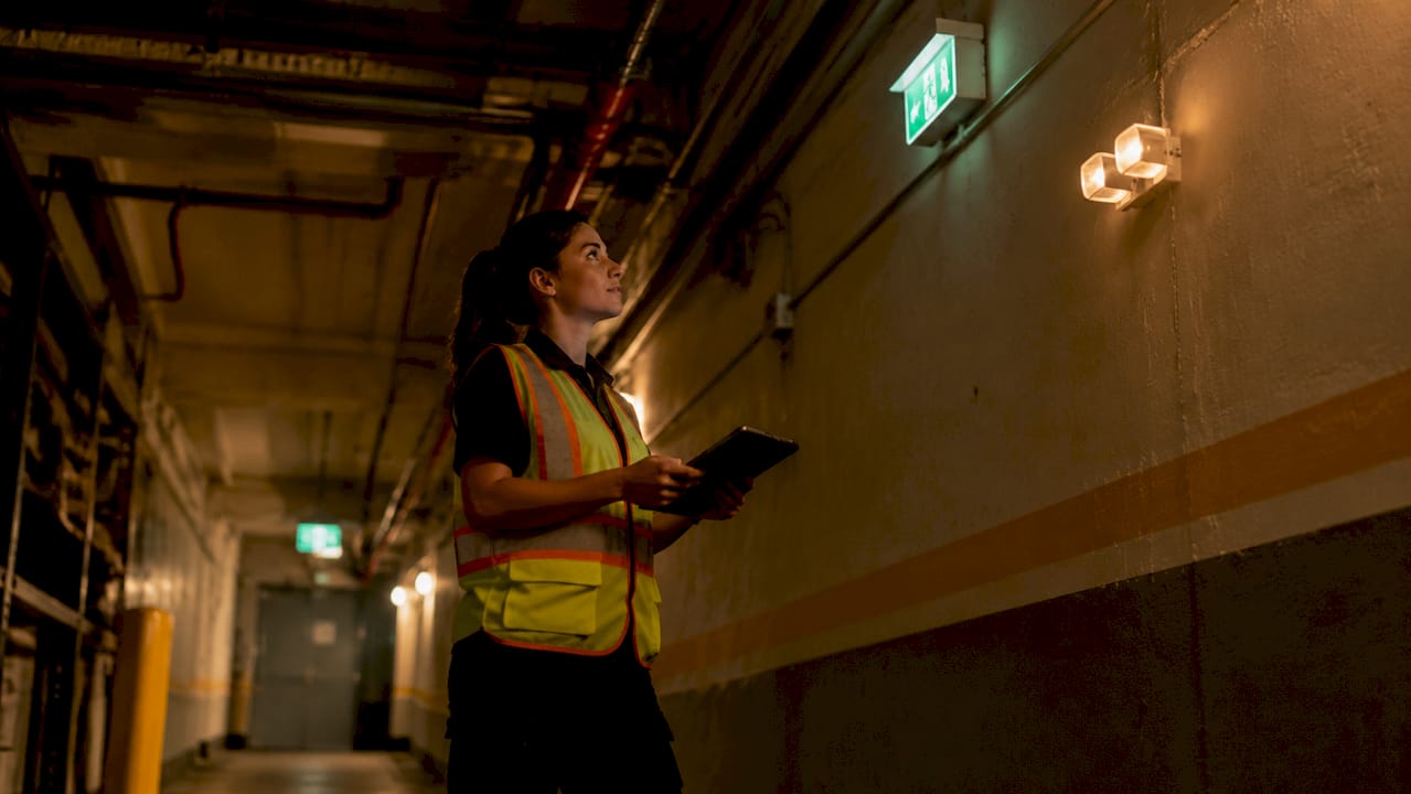 Facility technician inspecting egress corridor lighting