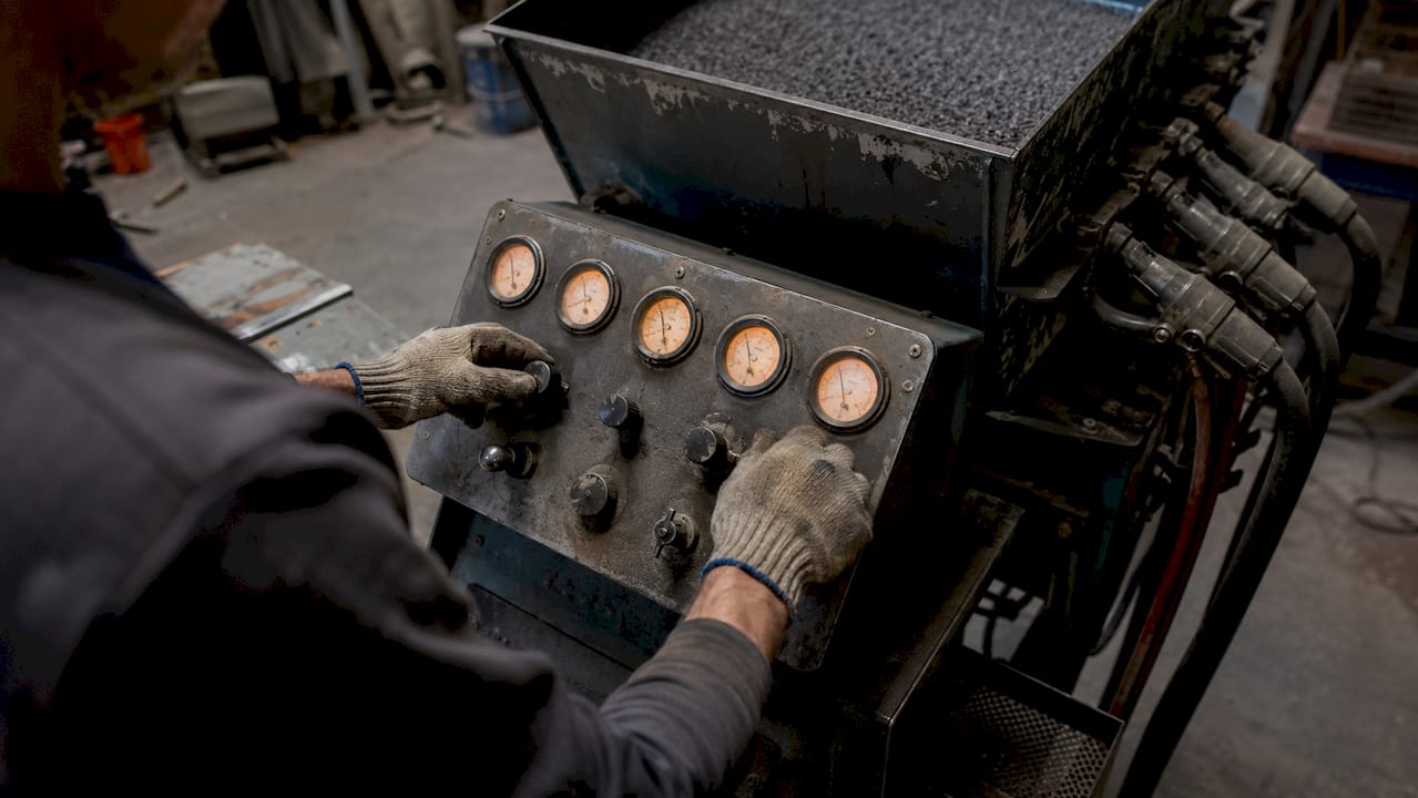 Close-up hands operating shot blasting machine controls