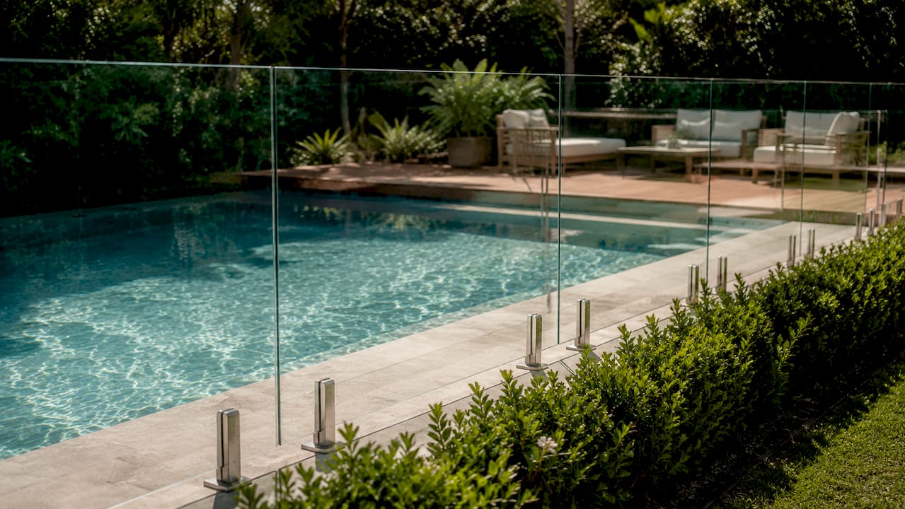 Close-up frameless glass pool fence with black spigots