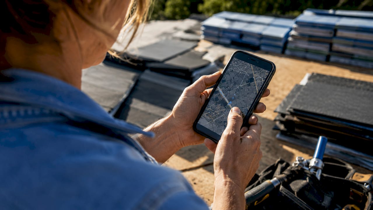 Close-up of roofer's hands holding smartphone outdoors