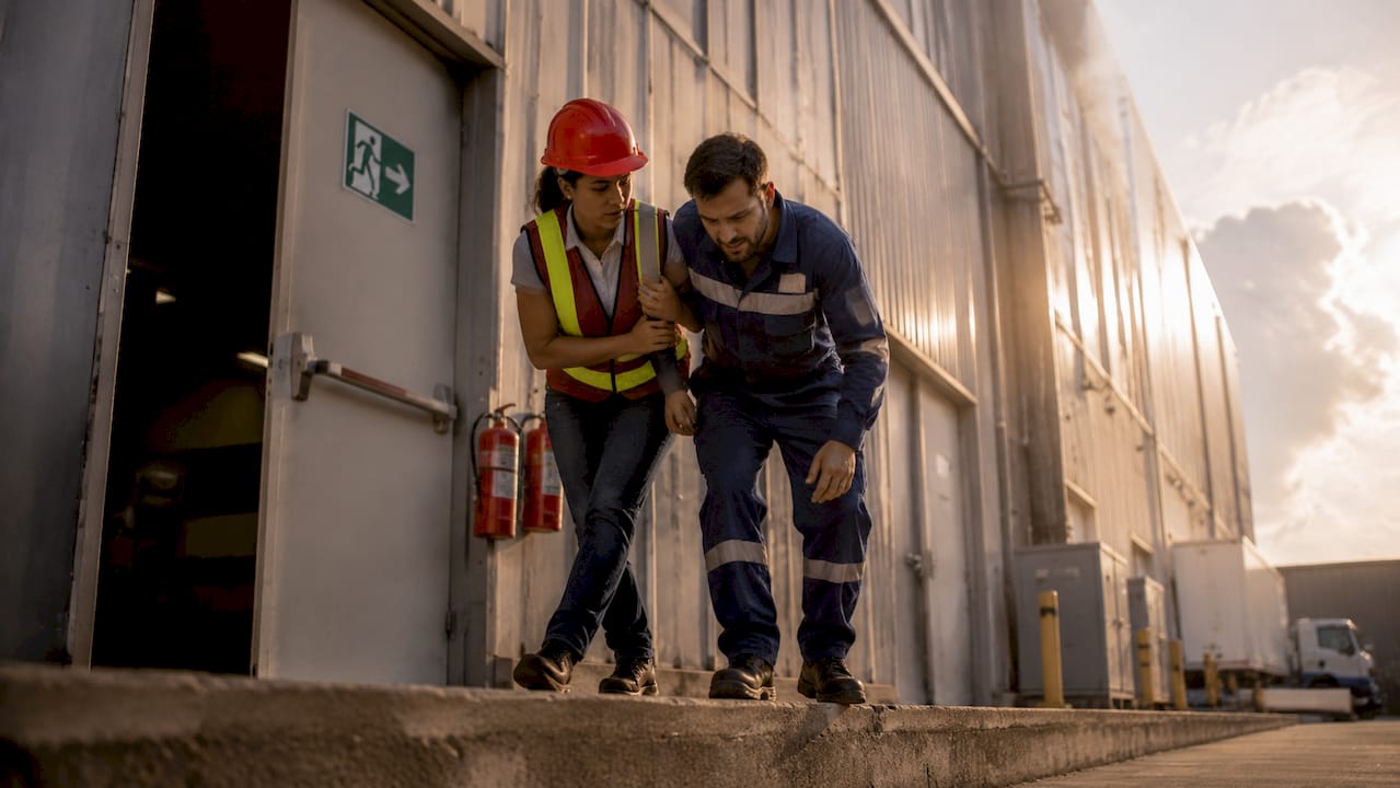 Woman helping injured coworker evacuate workshop