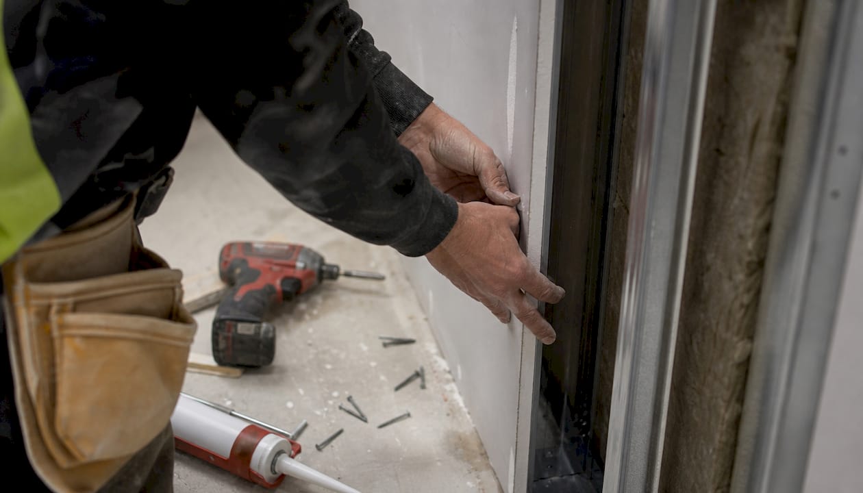 Hands installing fire-rated drywall panel