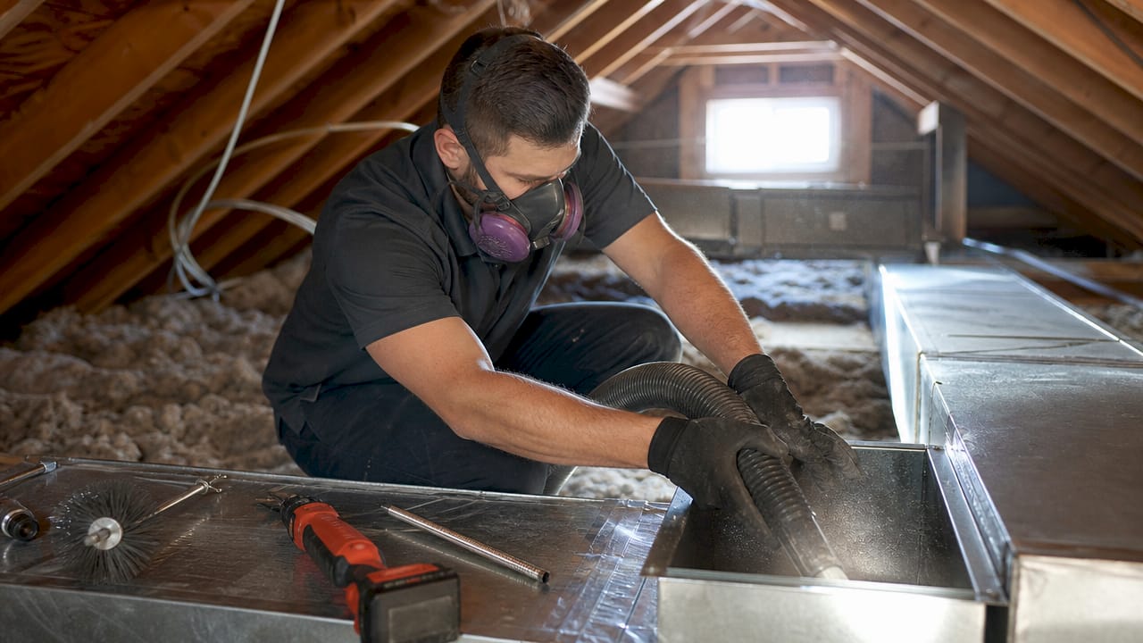 Technician cleaning HVAC duct in crawl space