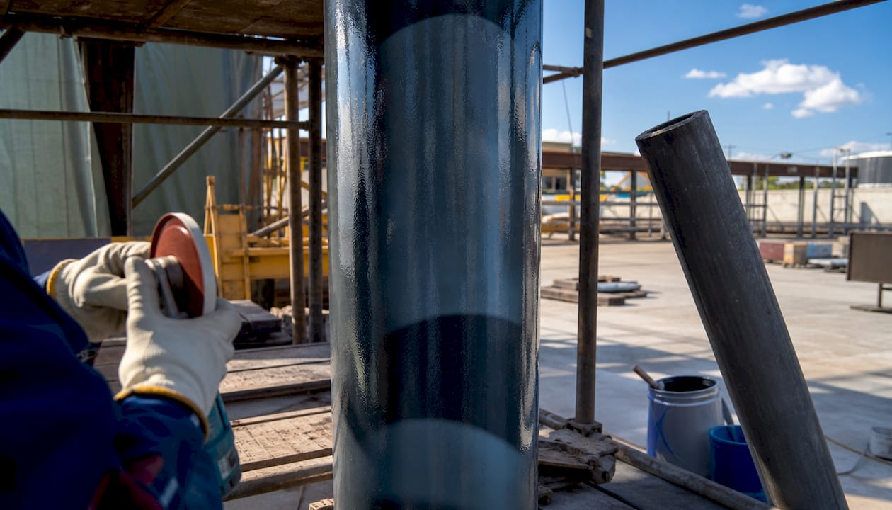 Close-up epoxy-coated steel pipe with worker’s hands