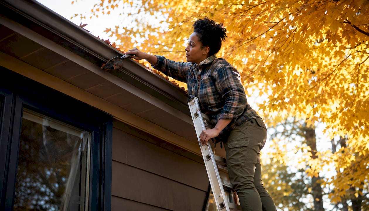 Woman trimming tree branches near gutters