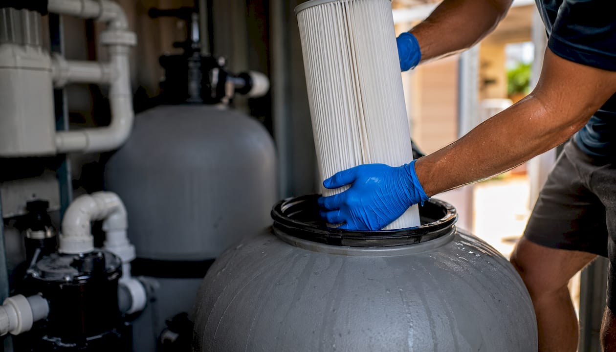 Hands replacing cartridge filter in pool system