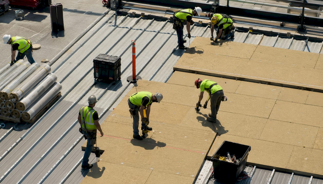 Team installing substrate boards on commercial low-slope steel roof