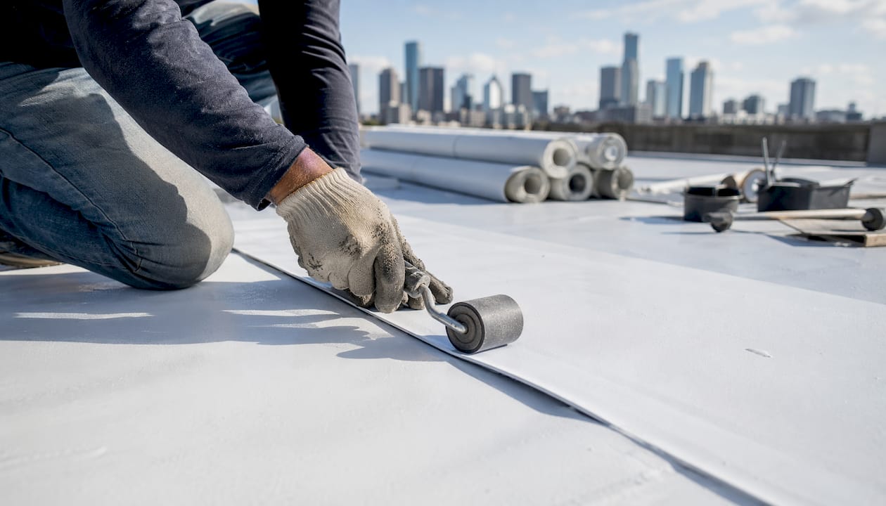 Hands installing reflective commercial roof membrane
